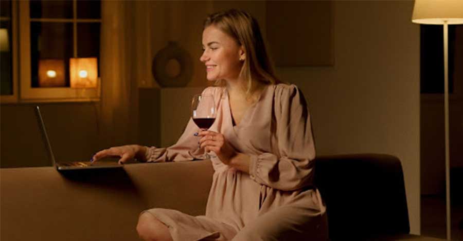 A woman smiling while holding a glass of red wine.