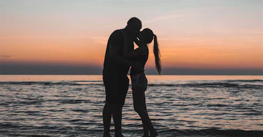 A couple kissing on the beach.