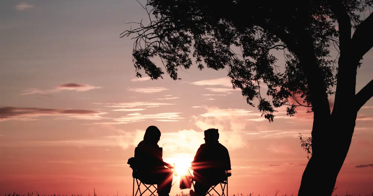  Couple sitting under a tree watching the sunset.