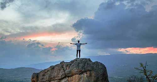 A photo of a man standing on top of a rock