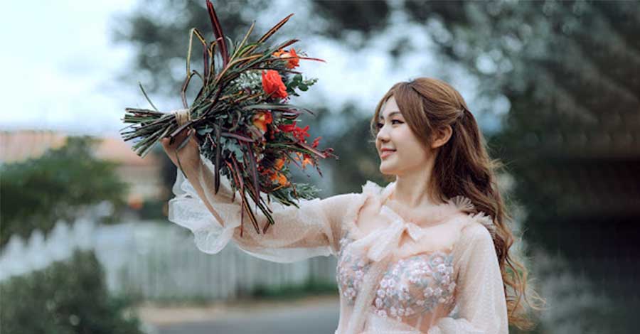 An Asian woman holding a flower.